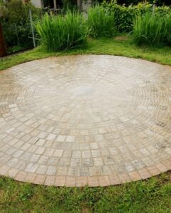 Präzise ausgeführte Rundpflasterung: Ein gepflastertes Rondell mit sauberem Verlegemuster und bündigem Abschluss zur Rasenkante. Ideal als Fundament für Gartenmöbel oder eine Feuerschale.